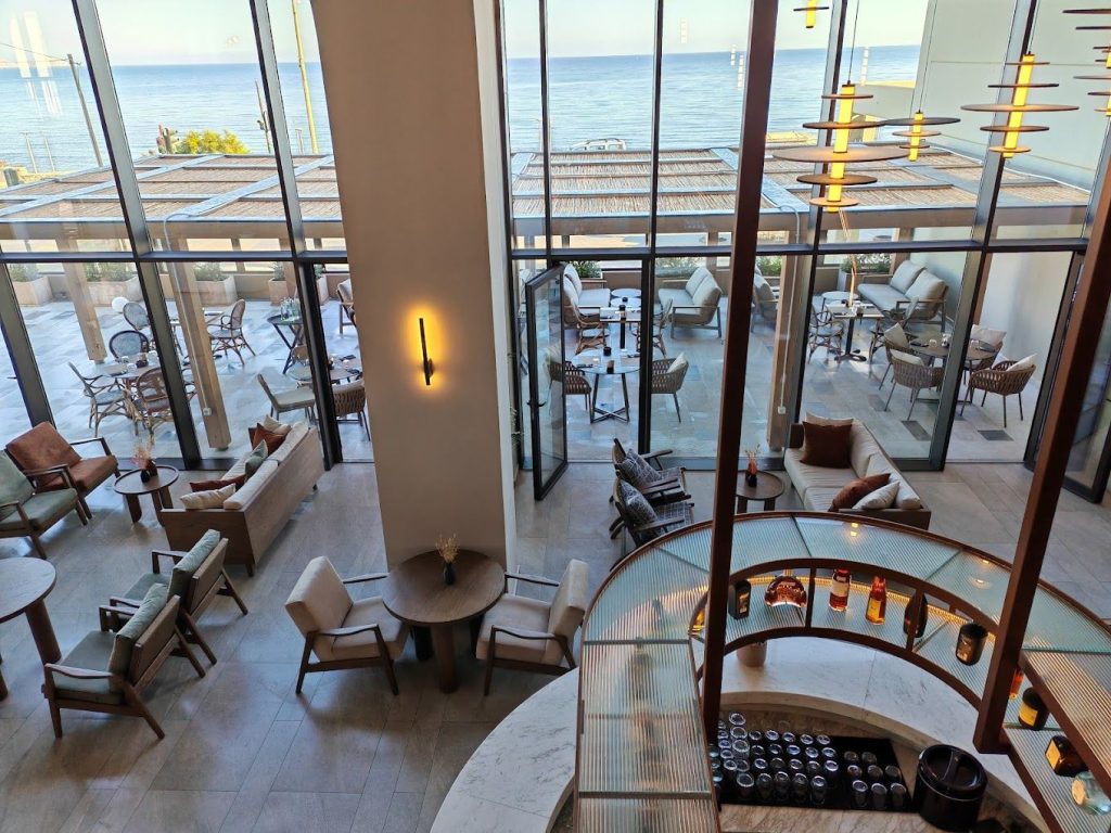 Double-height lounge with full-height glazing opening to a sea-view terrace