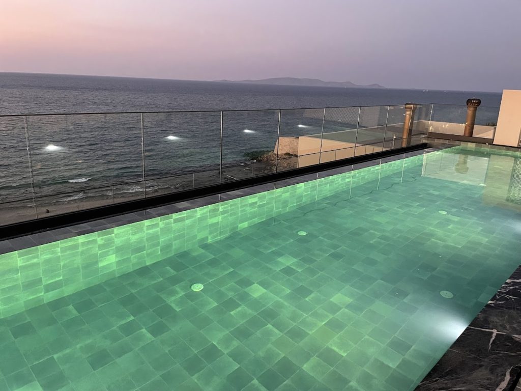 Illuminated rooftop pool overlooking the sea at dusk