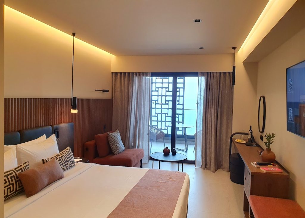 Guest room with balcony, sea view and warm timber detailing